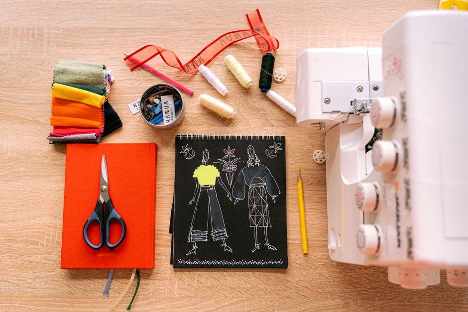 A vibrant sewing workspace featuring a sewing machine, fabrics, and design sketches on a wooden table.