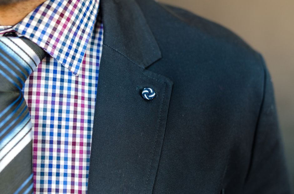 Detailed close-up of a man's checkered shirt, suit jacket, and striped tie.